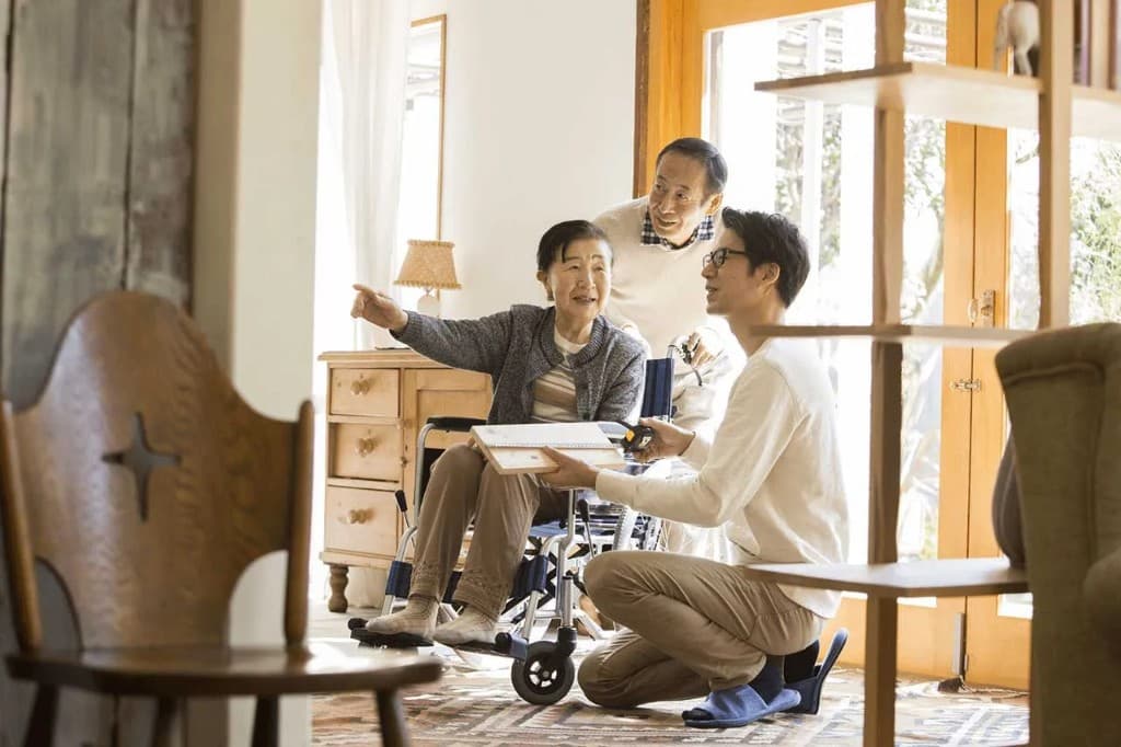 車いすの女性とご家族が、膝をついて話を聞くプランナーと居間でバリアフリーの相談をしている写真